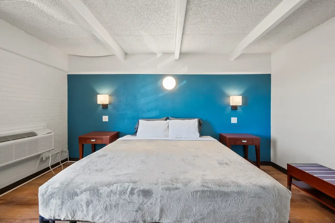 King room with a blue accent wall and wood floors